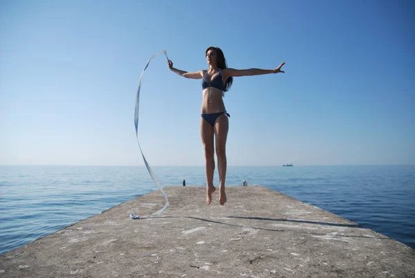 Girl with gymnastic ribbon posing on the beach on a sunny morning