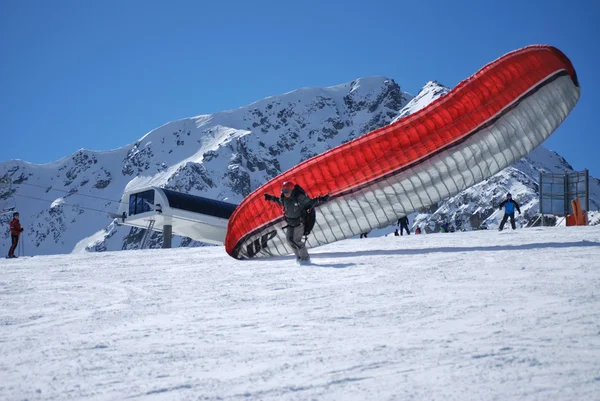 Paraglider dispersed on top of the mountain Todorka Bansko ski resort in Bulgaria on a sunny winter day.