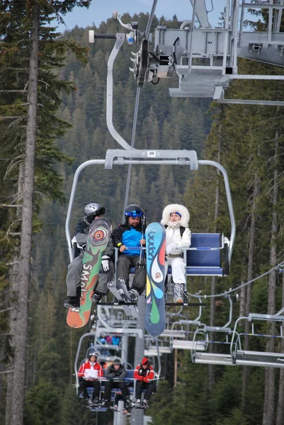 Company of young people rising on the chairlift to the top of the mountain Todorka Bansko ski resort in Bulgaria