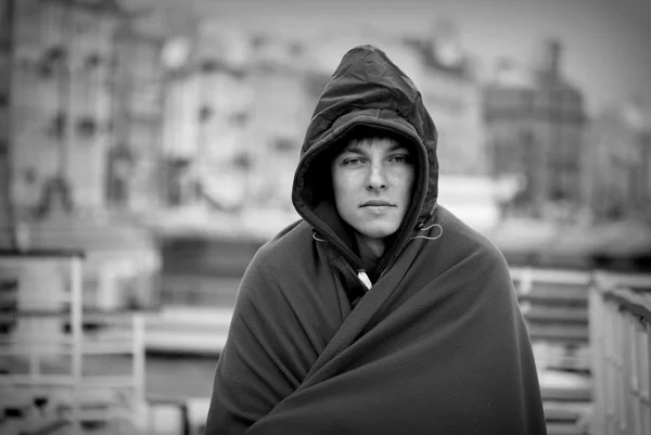 Young man basks under a blanket while riding on a boat on the Neva River in St. Petersburg