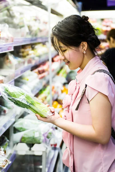 Woman choosing chinese cabbage at supermarket