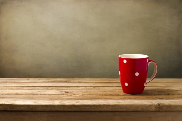 Red cup with dots on wooden table