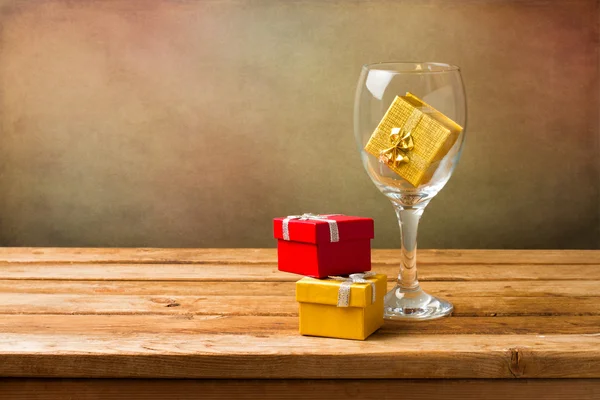 Empty wine glass with gift boxes on wooden table