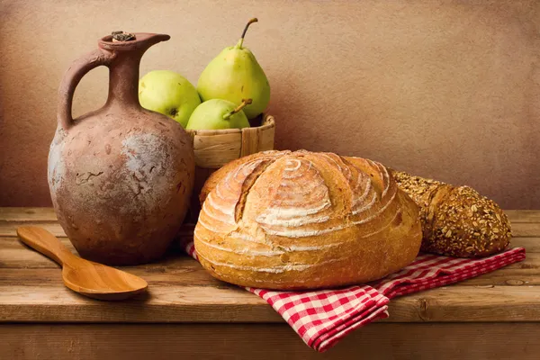 Still life with fresh bread and vintage jug on wooden table