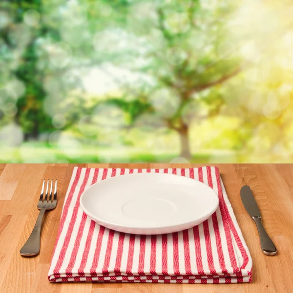 Empty plate with silverware on wooden table