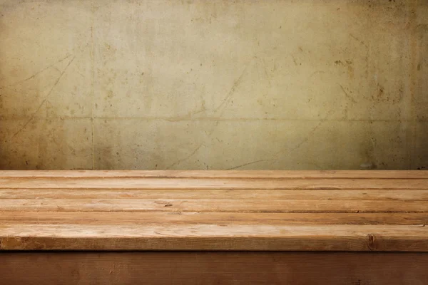 Empty wooden table over grunge concrete wall