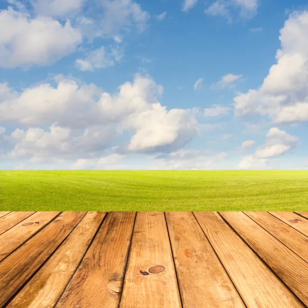 Wooden deck table over beautiful meadow with blue sky