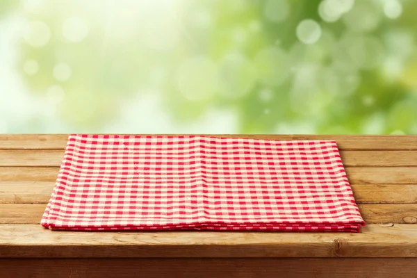 Empty wooden table with red checked tablecloth