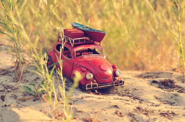 Toy car with luggage on sandy beach