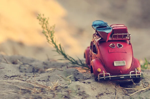 Toy car with luggage on sandy beach