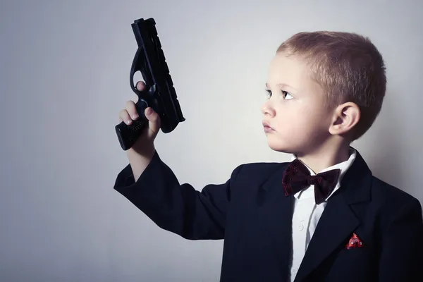 Little James Bond. Fashionable Little Boy in Bow tie.Stylish Agent. Fashion Children. 4 Years Old Child in Black Suit. Elegance Handsome Boy with Gun.