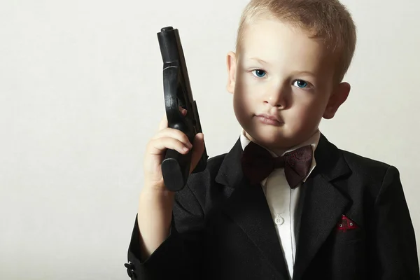 Handsome Boy with Gun.Fashionable Spy in Suit .Stylish Agent 007. Fashion Children.Child in Bow tie. Elegance. Little James Bond