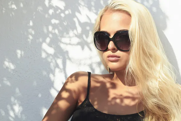 Beautiful woman in sunglasses.shadows. beauty blond girl in near the wall. Summer style