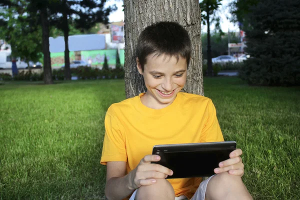 Boy teenager play Tablet PC outdoor summer park