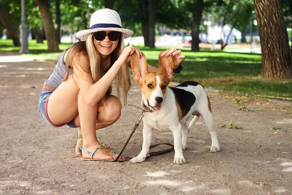 Happy young woman playing with Beagle dog outdoors . funny shot