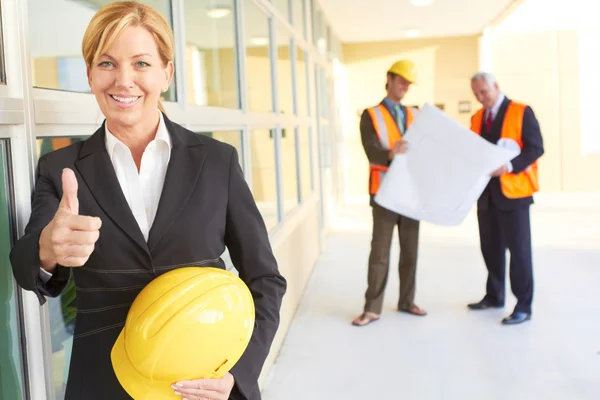 Happy confident business woman holding hardhat giving thumbs up