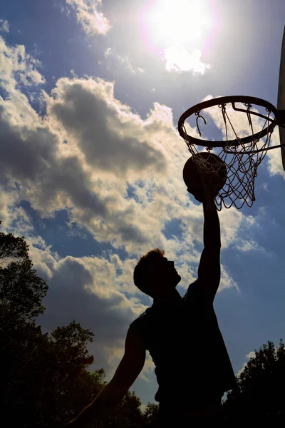 Silhouette of young man playing basketball