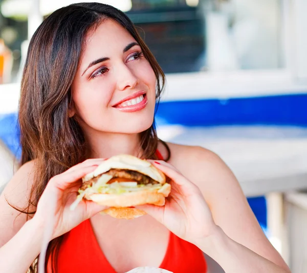 Beautiful happy young latin girl eating hamburger