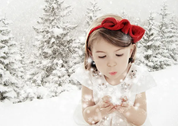 Three years old girl blowing smowflakes in winter landscape
