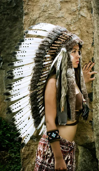 Native american, Indians in traditional dress, standing in profile next to the stone slabs. American indian Girl