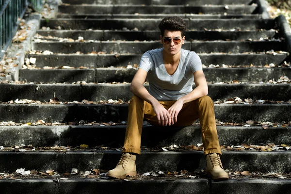 Attractive young handsome man, model of fashion in stairs