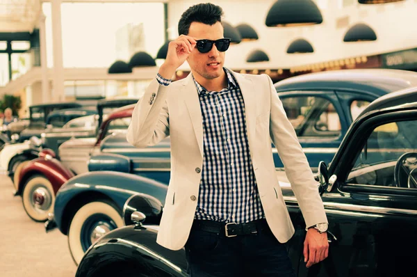 Attractive man wearing jacket and shirt with old cars