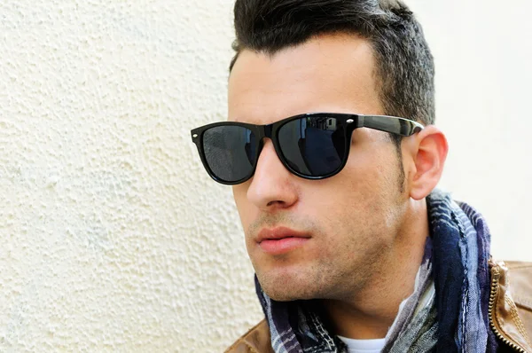 Attractive man wearing tinted sunglasses in urban background