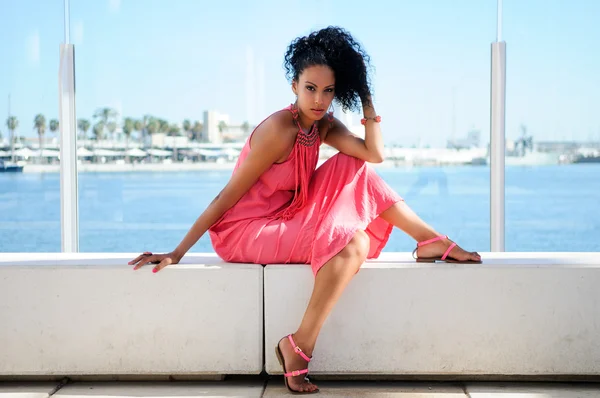 Portrait of a young black woman, model of fashion, with pink dress and earrings. Afro hairstyle