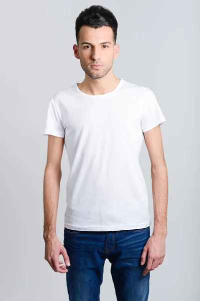 Serious young man standing against white background