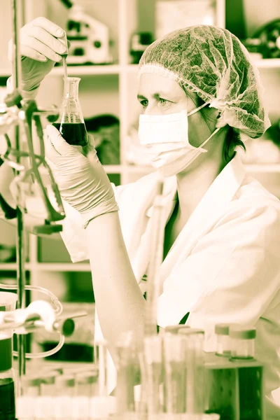Scientific researcher holding at a liquid solution in a lab