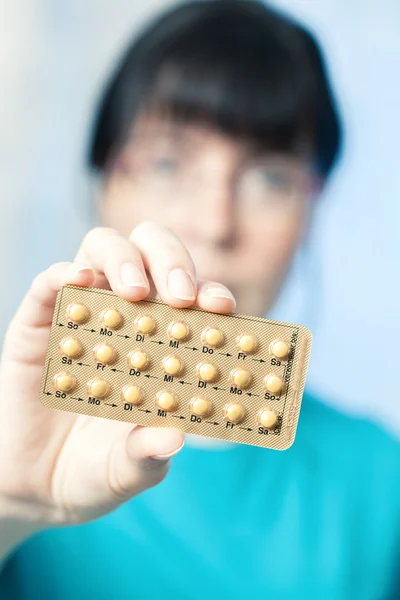 Young woman holds birth control pills