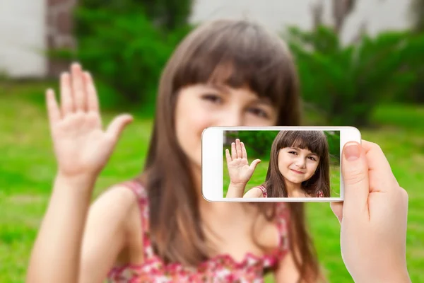 Female hand holding a phone with video call of little girl on th