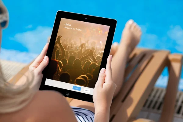 Girl lying on a sun lounger by the pool and holding iPad with Tw