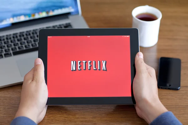 Male hands holding iPad with app Netflix on the screen in the of