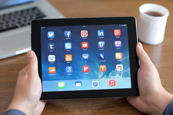 Male hands holding iPad with social media app on the screen in t