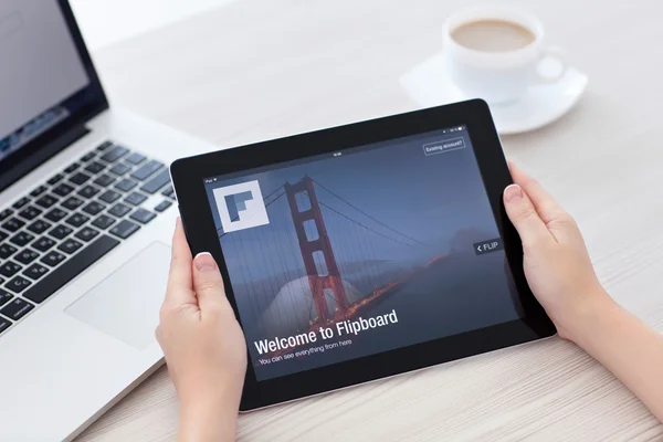 Female hands holding iPad with app Flipboard on the screen in th