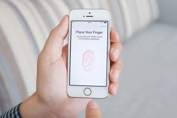 Man holding a white iPhone 5s with Touch ID on the screen