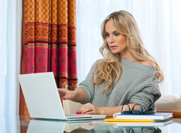 Attractive blond woman writing on laptop