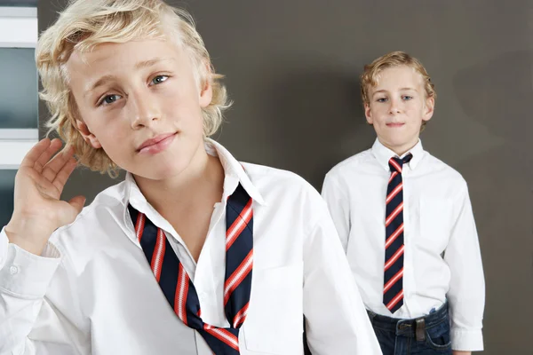 Two brothers getting ready for school at home, wearing uniform shirts and ties.