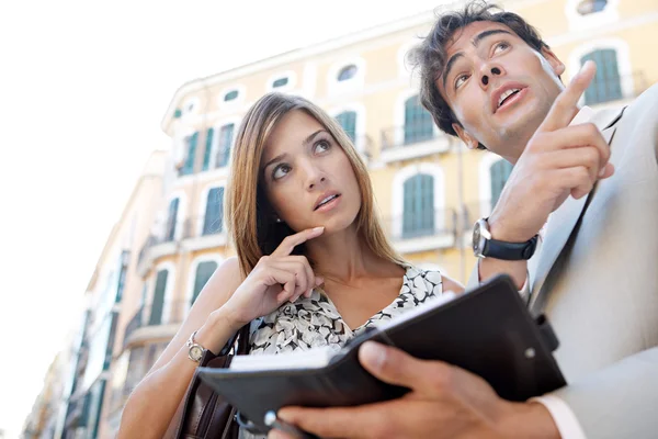 Businessman and businesswoman laughing while having a meeting outdoors, in a classic city