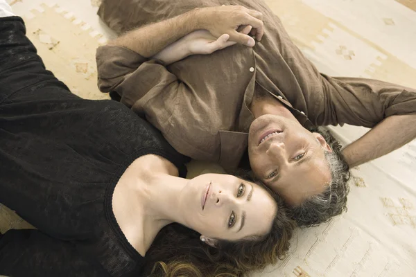 Over head portrait of a mature man and woman laying down on carpet