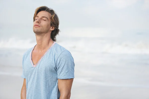 Attractive man breathing fresh air while on the beach