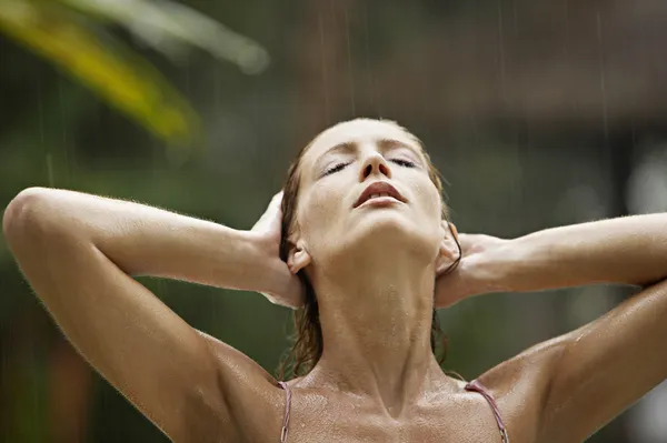 Attractive young woman under the tropical rain