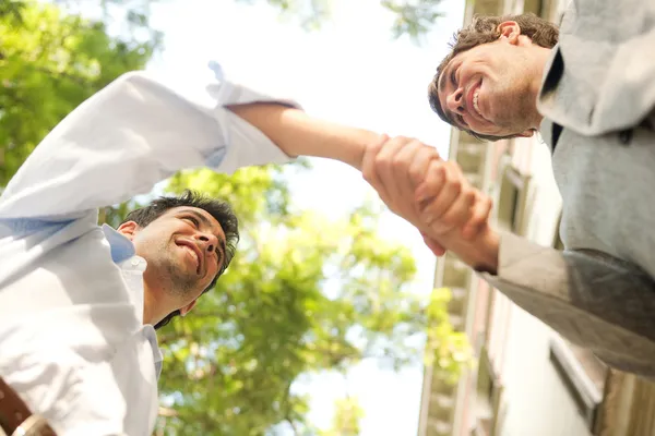 Two young attractive businessmen shaking hands