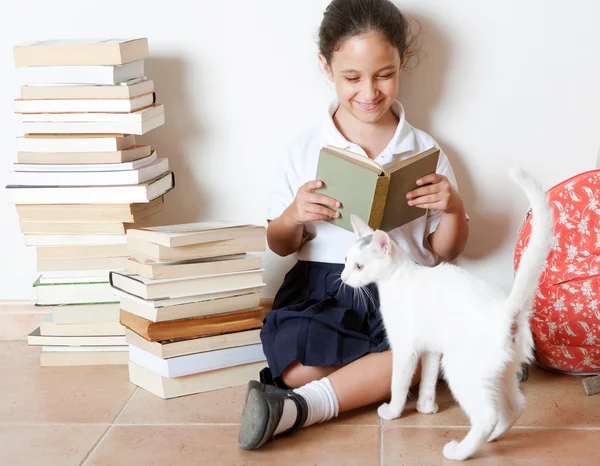 Young girl reading a book with her cat at home