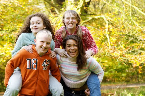 Four young teenager friends playing piggy bag