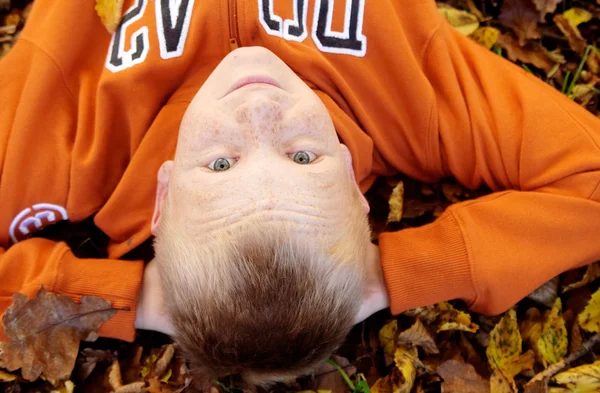 Boy with freckles laying down on leaves