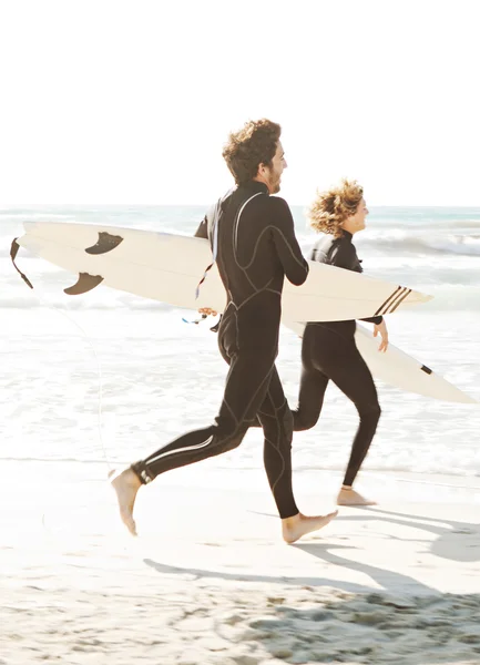 Surfers running together
