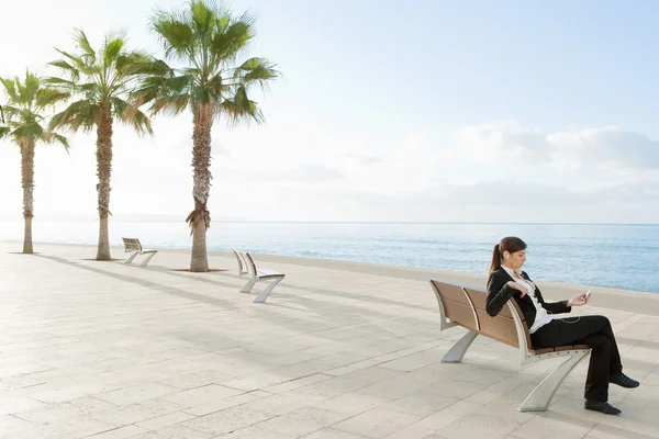 Businesswoman sitting on a wooden bench by the sea