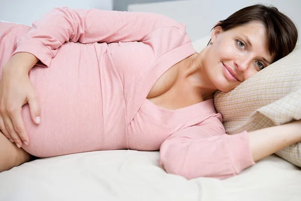 Pregnant woman laying down on bed